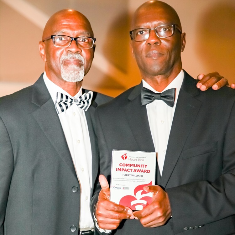 Two gentlemen holding Community Impact Award for Harry Williams.